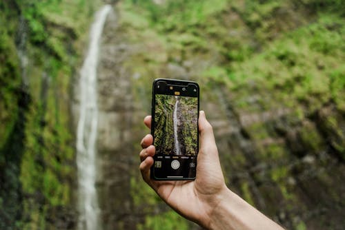 
A Person Taking a Picture of a Waterfall