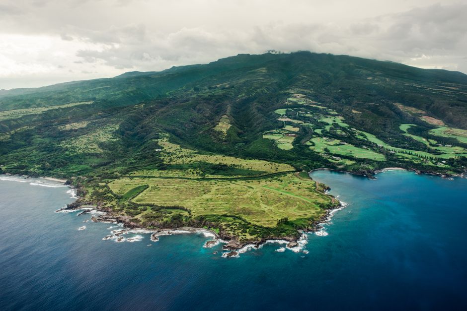 Incredible Big Island Spectacular Helicopter Tour Review: The Ultimate 2-Hour Volcanic Adventure Review 2026 - Stunning aerial view of lush green hills and coastline meeting the blue ocean under an overcast sky.