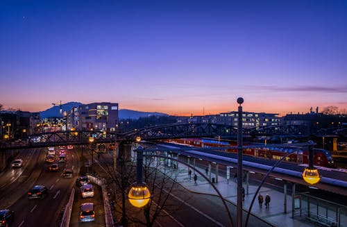 Menschen, Die Auf Bahnhof Nahe Autobahn In Der Ferne Von Gebäuden Gehen