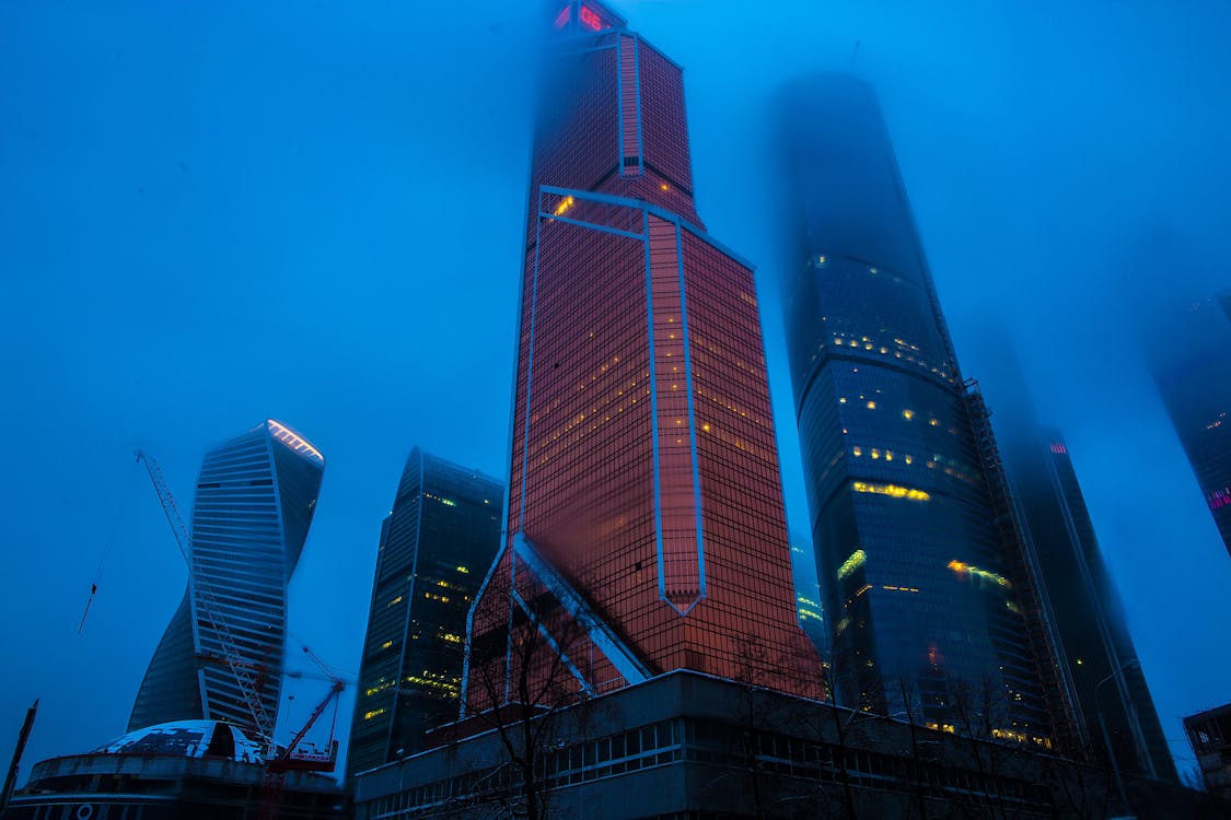 Free Low Angle Photography of High Rise Buildings Covered With Fogs Stock Photo