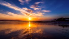 宁静的海滩上，日落令人惊叹，倒影缤纷