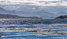 多云天空下，海景华丽，有山脉和桥梁