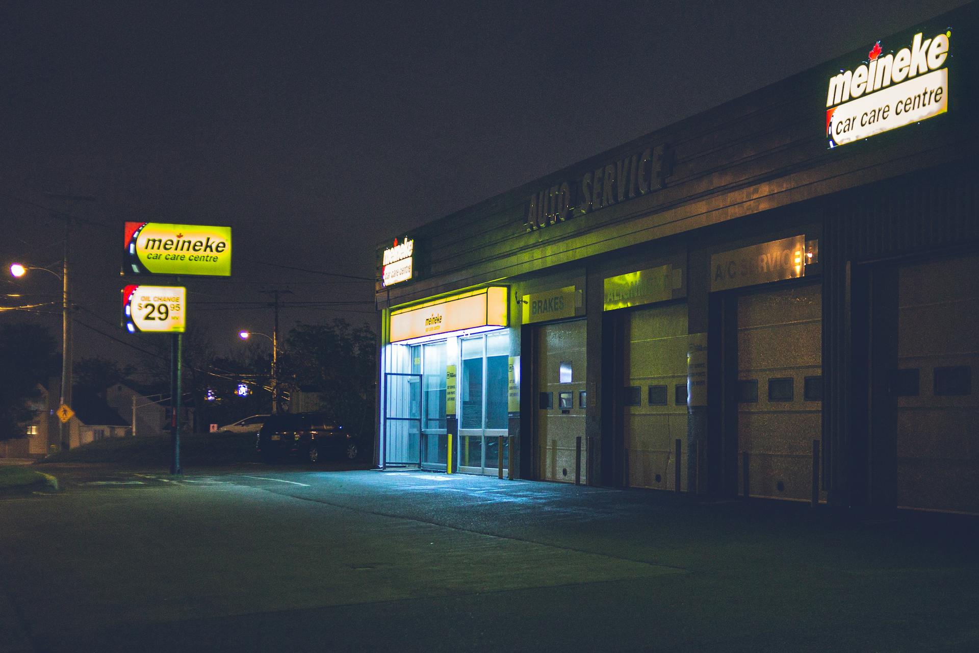 Night view of an illuminated auto service center with signage lights glowing.