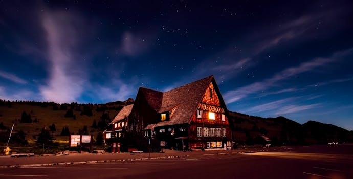 A beautiful lodge illuminated under a starry night sky, creating a serene and inviting landscape.