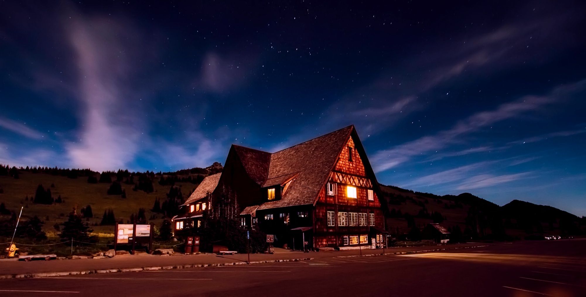 A beautiful lodge illuminated under a starry night sky, creating a serene and inviting landscape.