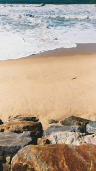 A scenic view of a sandy beach with rocks by the shore in Ovar, Portugal.