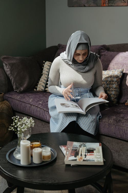 Donna In Hijab Bianco Che Si Siede Sul Giornale Della Lettura Del Divano