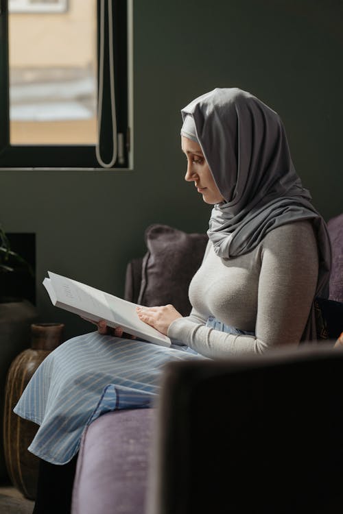 Mujer, En, Gris, Hijab, Sentado, En, Silla, Libro De Lectura