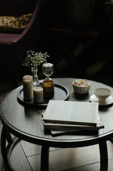 舒适的咖啡桌上摆放着书籍、蜡烛和一杯茶，非常适合放松休息