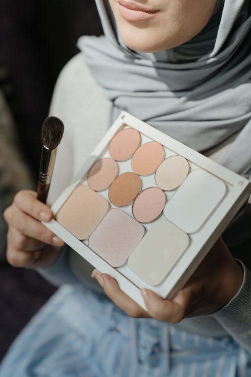 Person Holding Makeup Brush and Makeup Palette