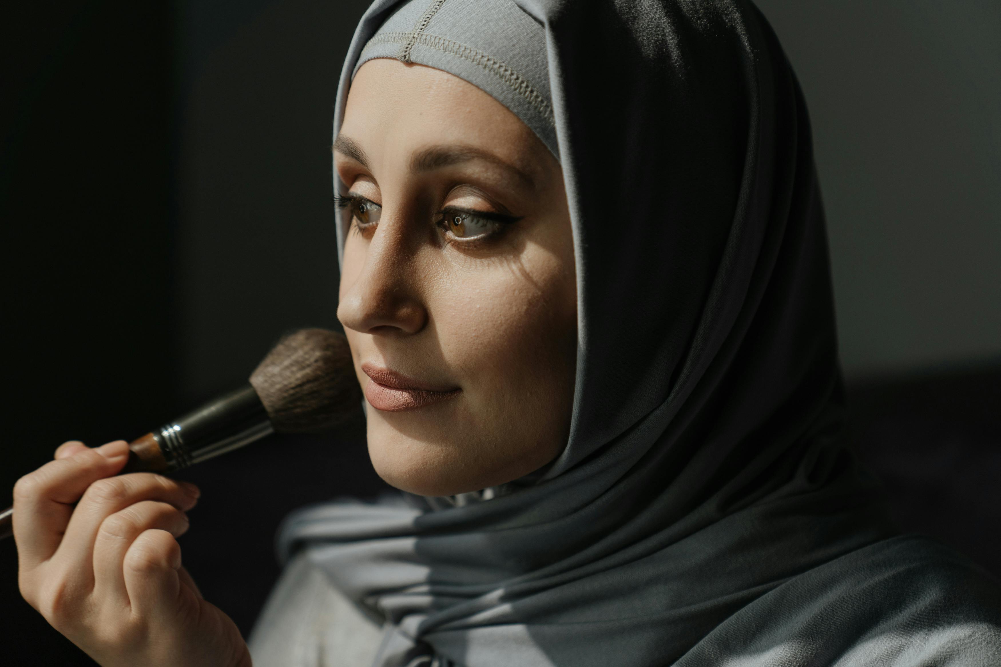 woman in black hijab holding makeup brush