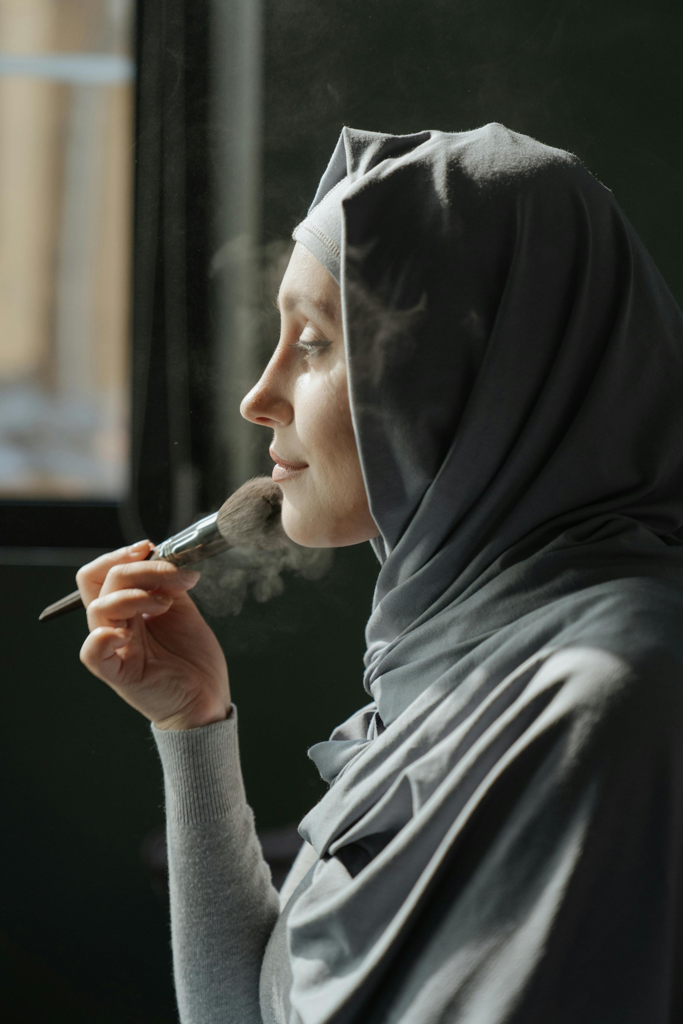 woman in gray hijab holding black smartphone