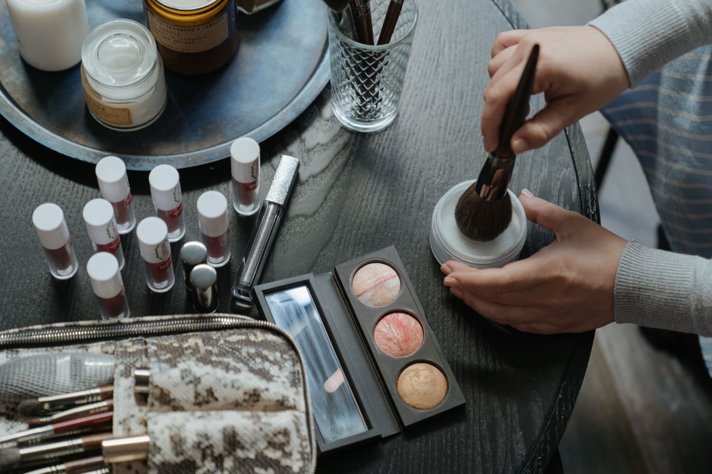 Palette de maquillage ouverte, pinceaux et rouges à lèvres posés sur une table