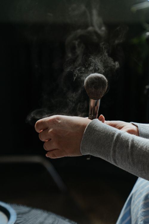 Free Close-up of hand using makeup brush indoors with powder dust effect. Stock Photo