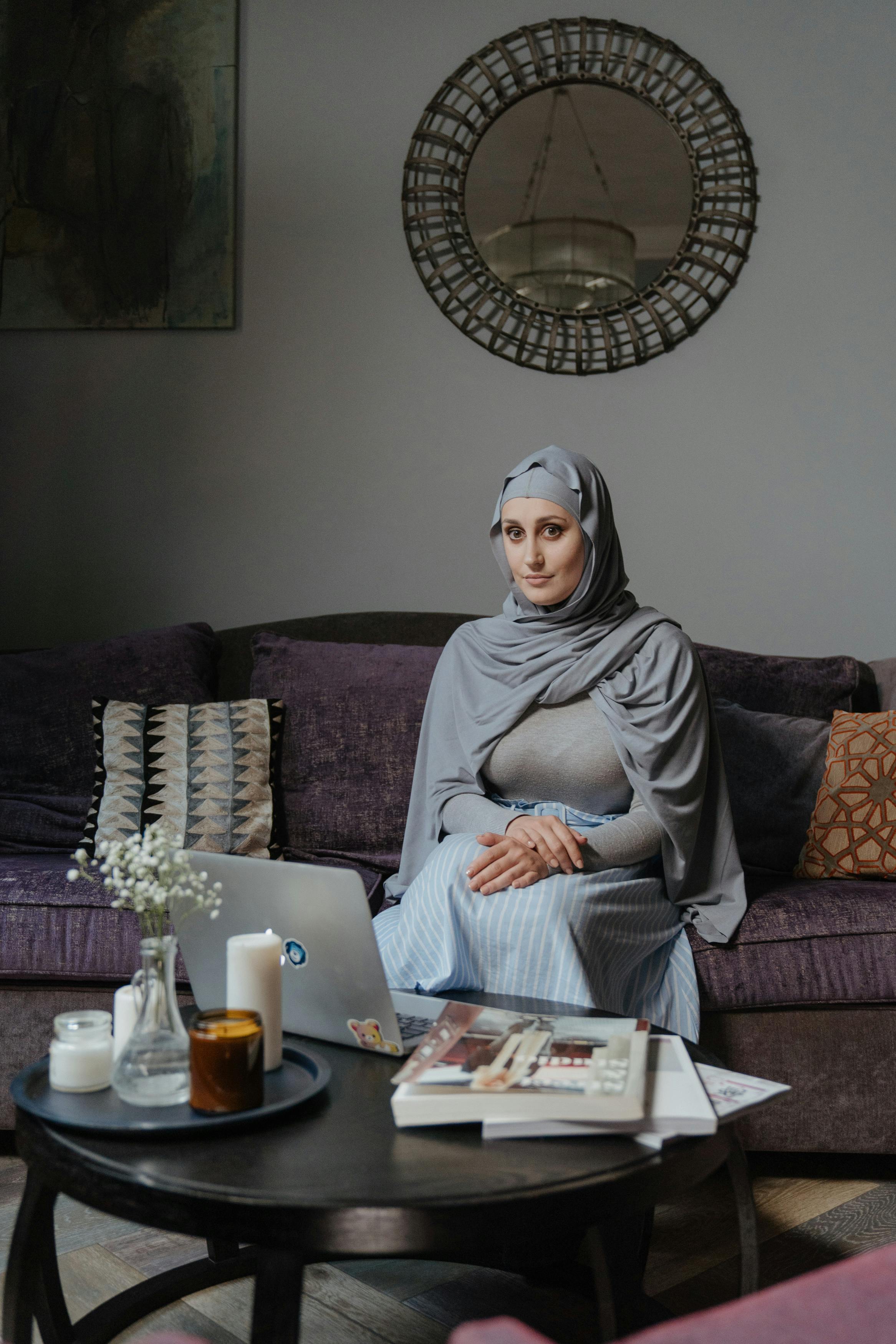 一位穿着传统服装的女人，带着笔记本电脑，坐在时尚的客厅里