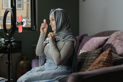 一名戴头巾的女子在室内用智能手机和铃声录制化妆教程