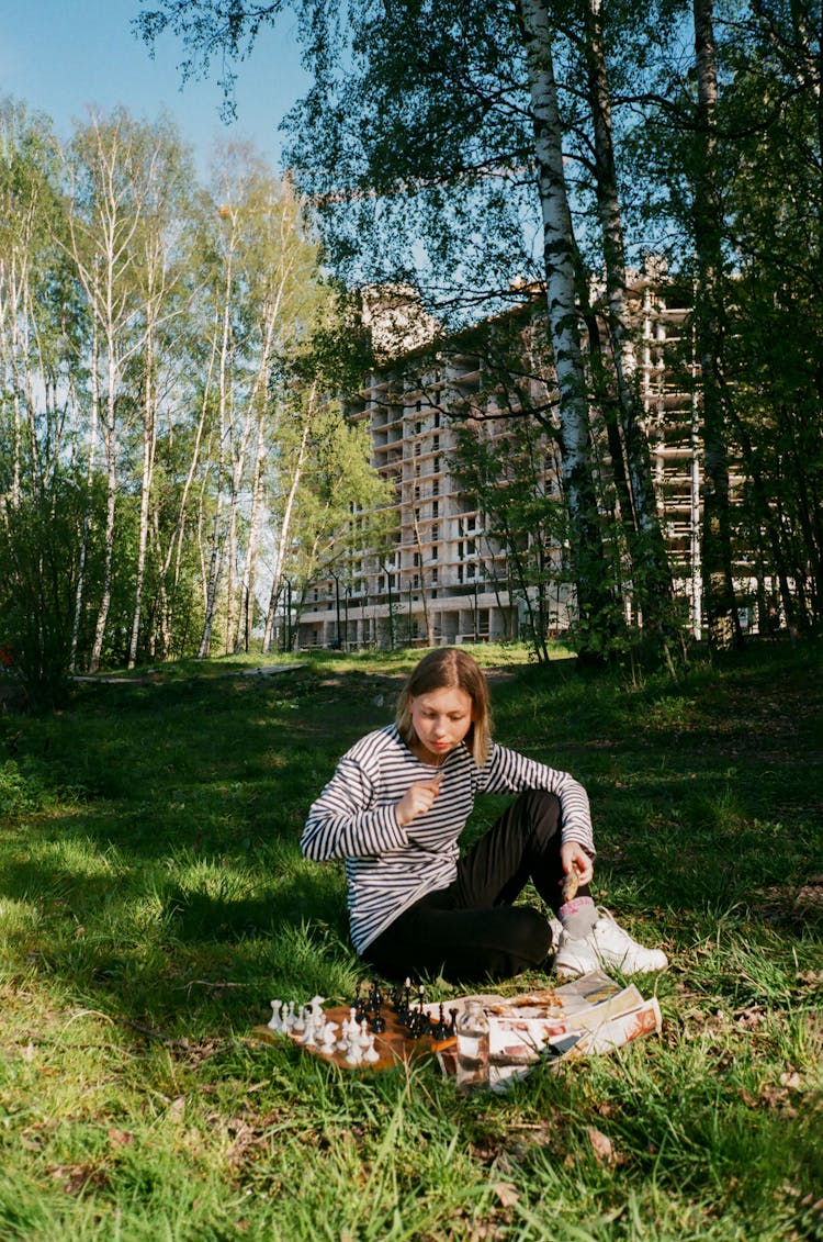 Young Woman Playing Chess In Park