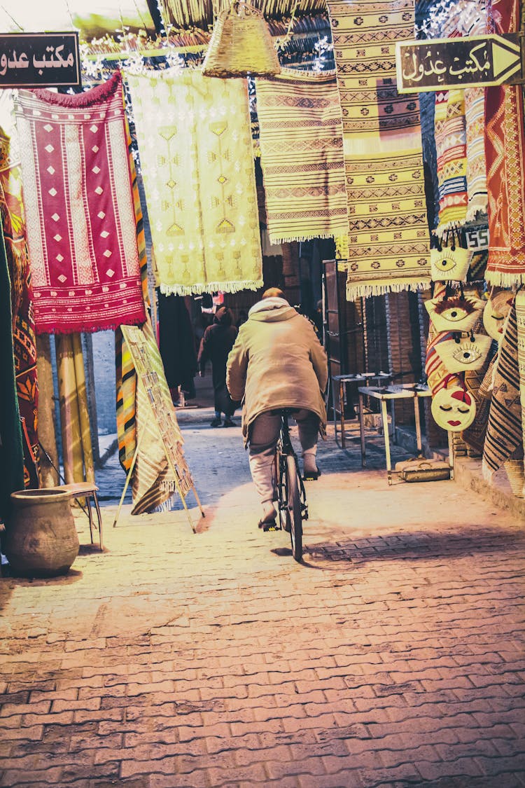 Unrecognizable Person Riding On Bicycle Through Market