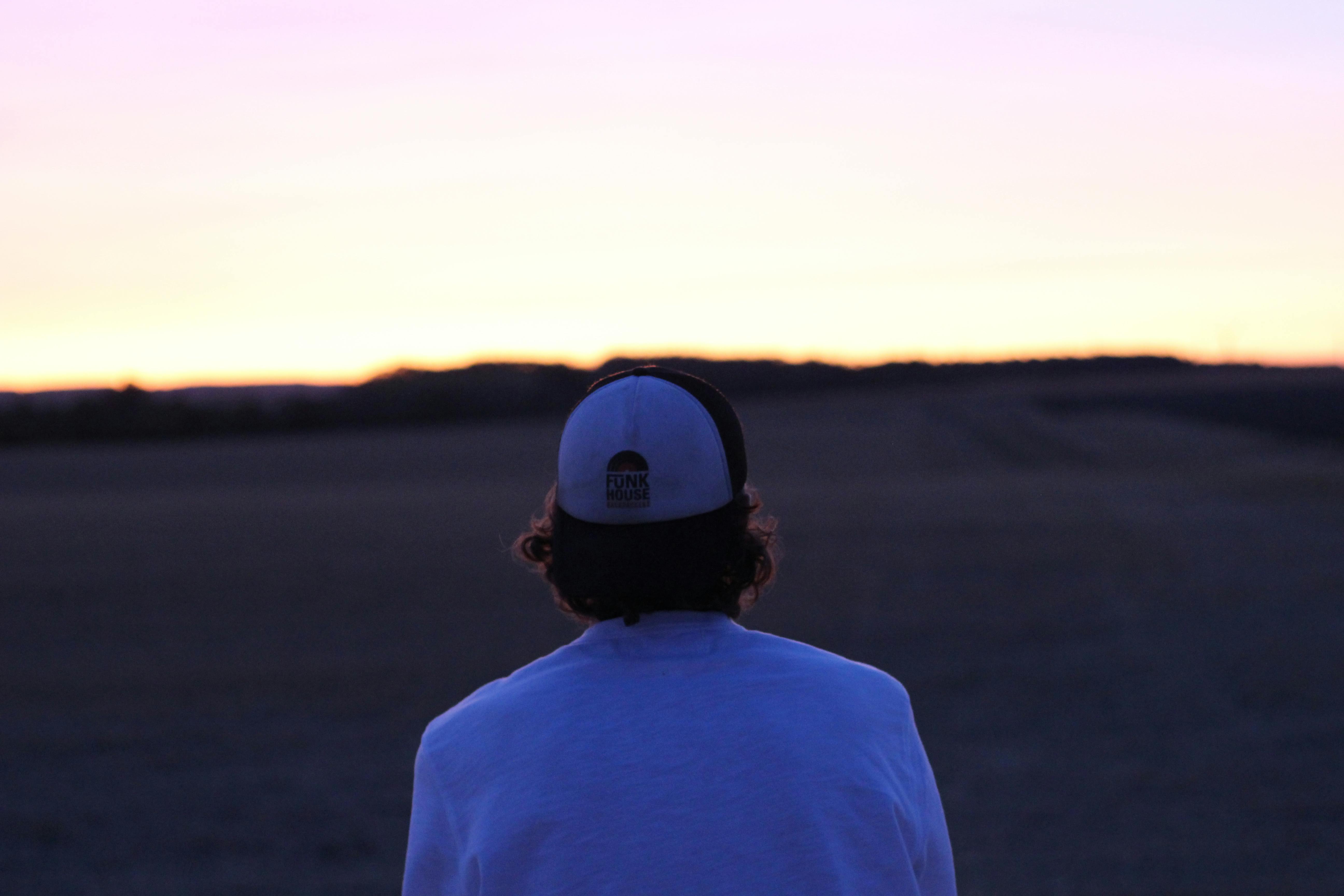 Woman's hand loosely holding silk ribbon on soft bedding, rain-blurred window in background, sensual anticipation mood