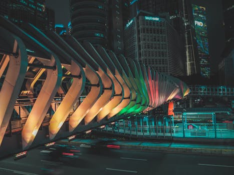 Dramatic view of an illuminated modern bridge in Jakarta cityscape at night.