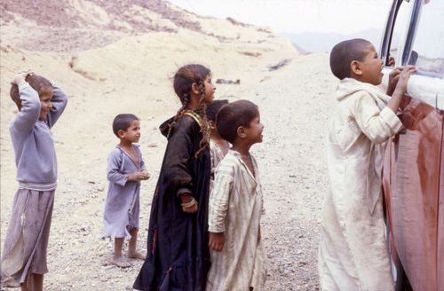 Free Group of children examining a vehicle in a rural, arid desert environment. Stock Photo