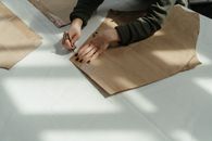 Person in Black and Gray Long Sleeve Shirt Holding Brown Wooden Board