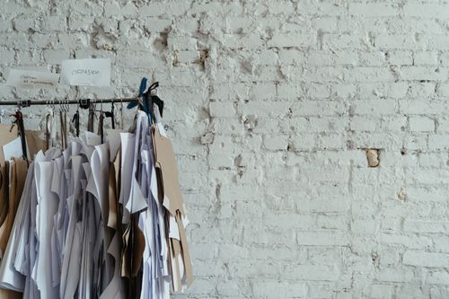 Free A collection of sewing patterns hanging against a textured white brick wall, offering space for text. Stock Photo