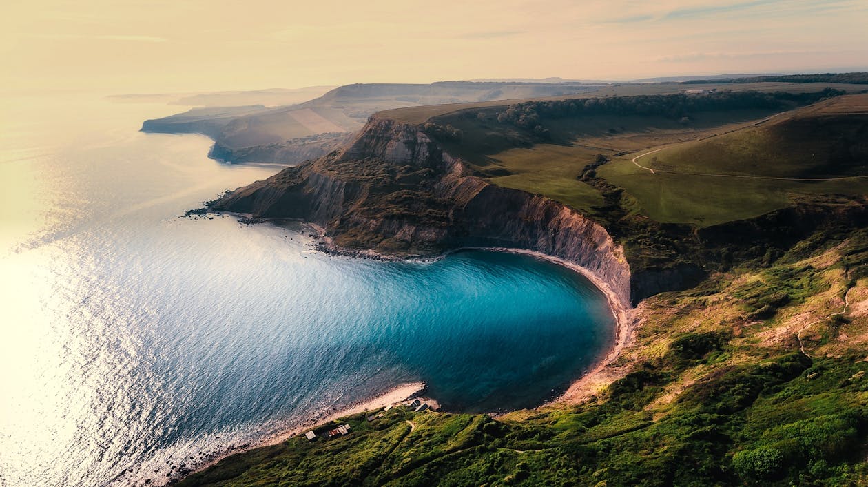 Free Green Hill Near Body of Water Stock Photo