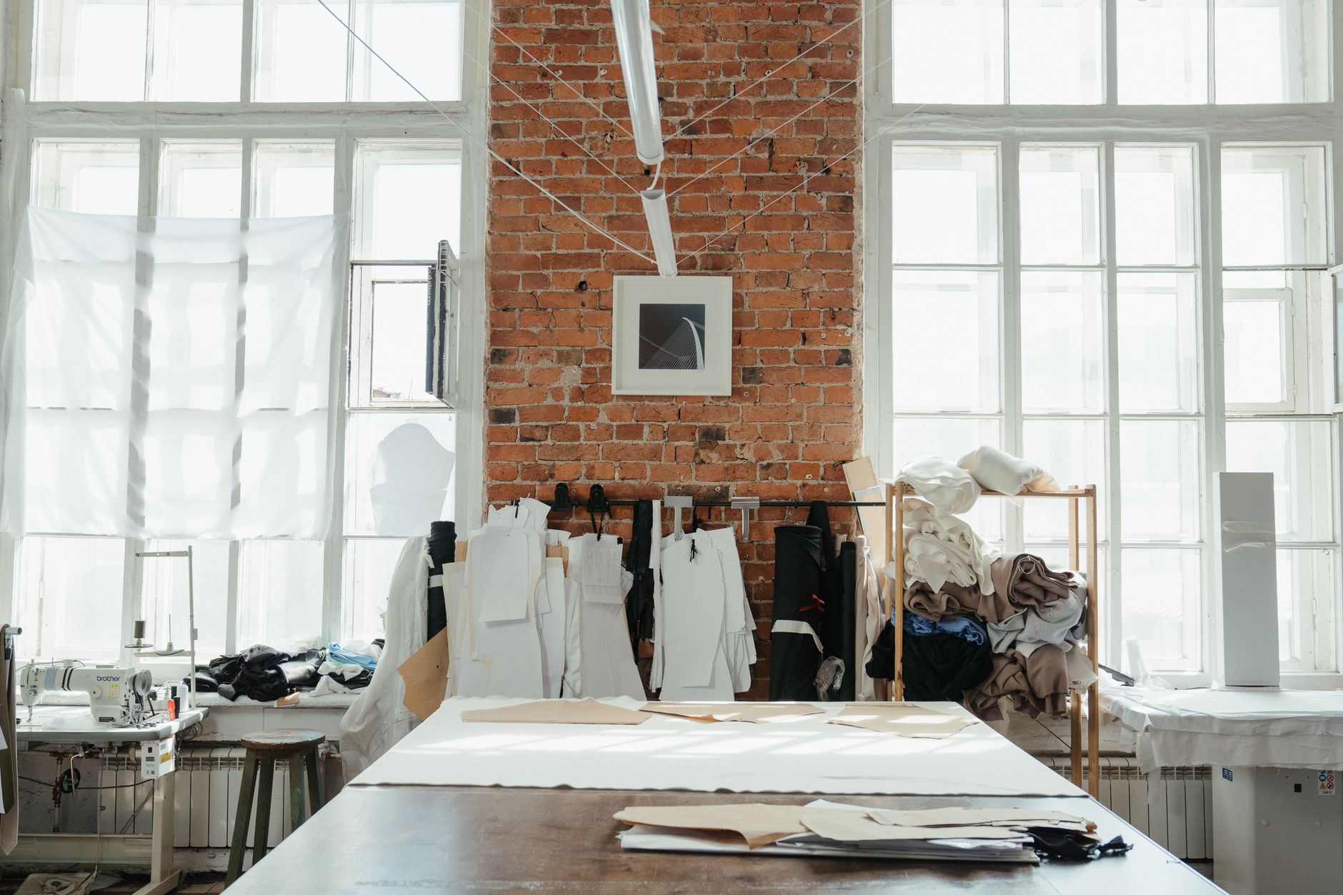 Bright sewing studio interior with brick walls and fabric