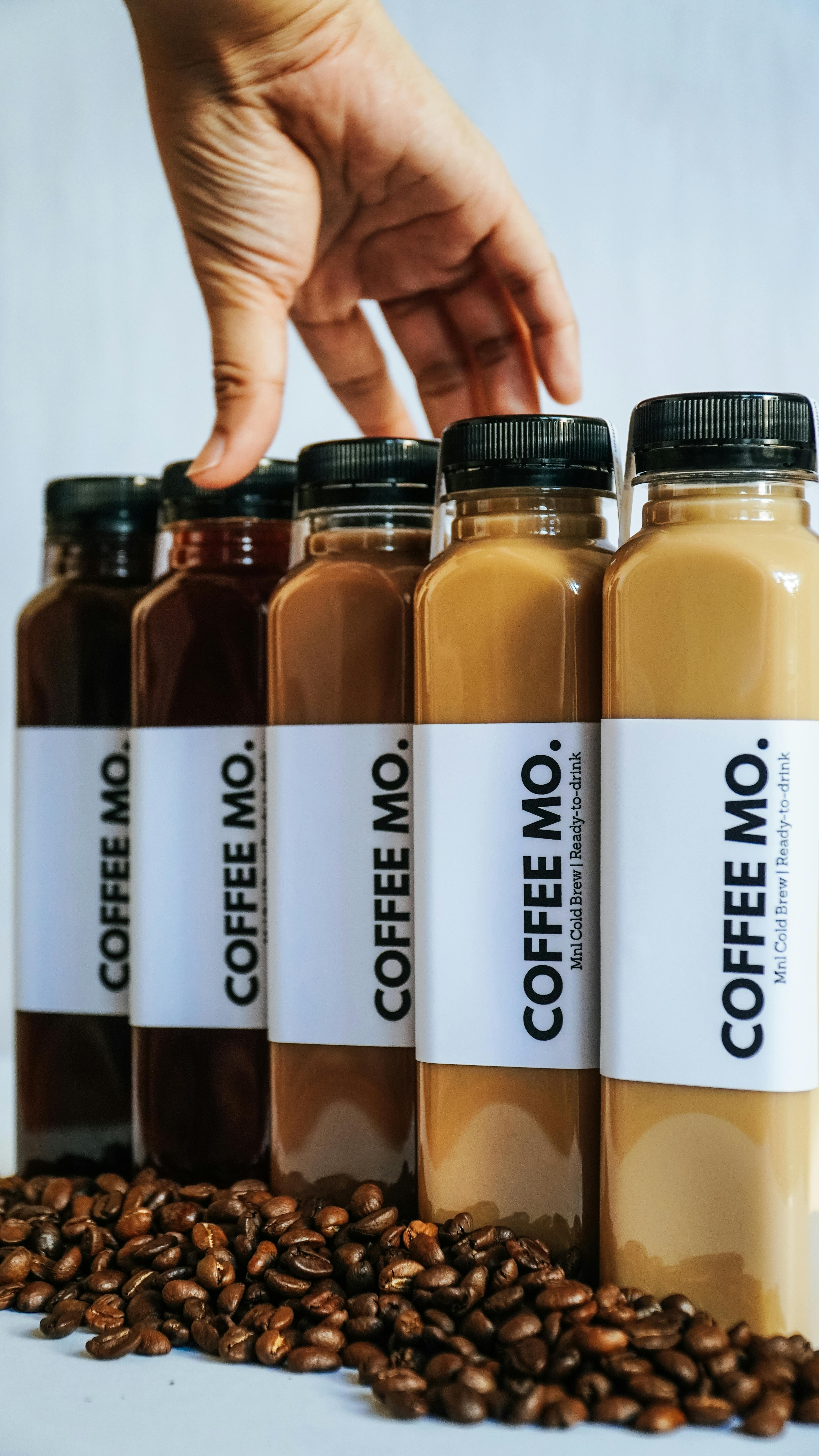 crop person touching bottles with various coffee drinks