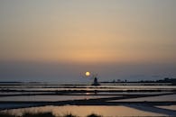 风车倒映在水中，与日落一同构成宁静而风景如画的景象