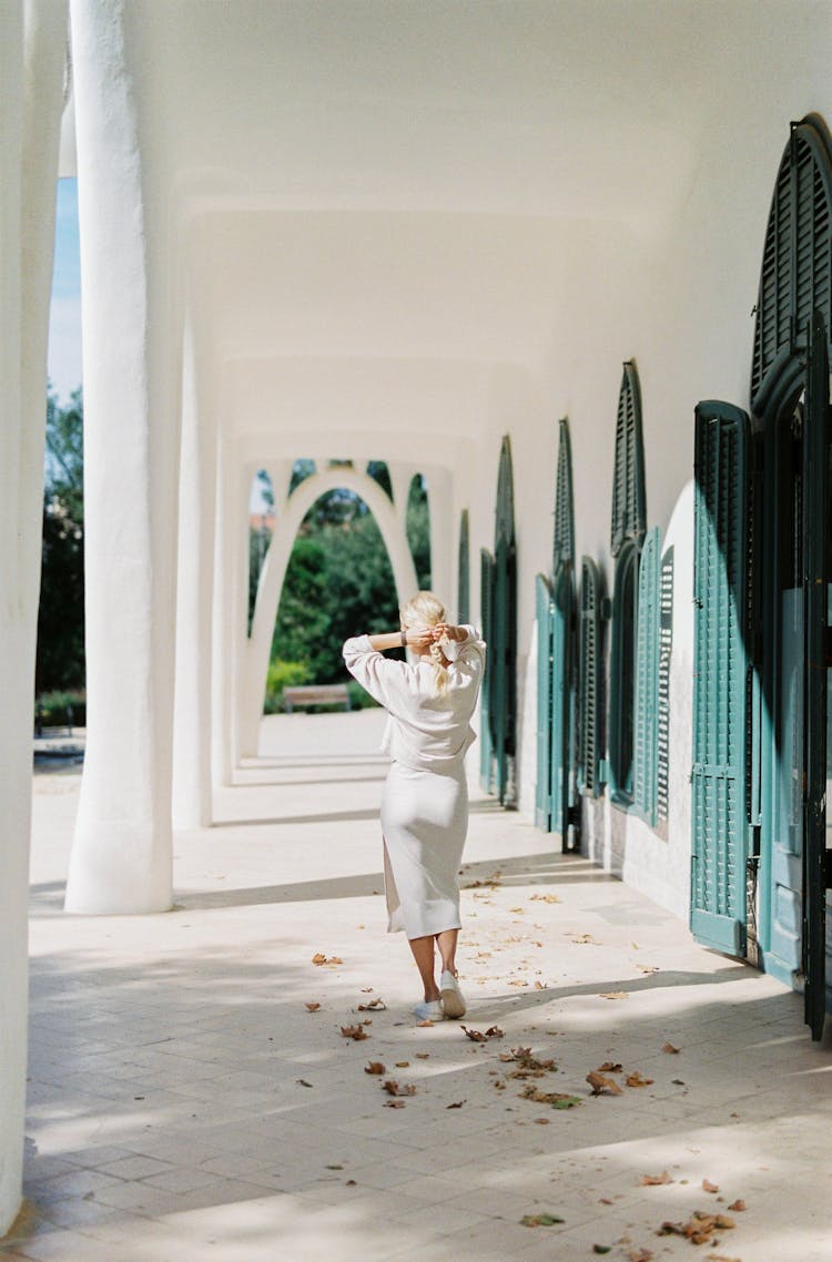 Woman In White Clothes Walking On Outdoor Hallway Of A House