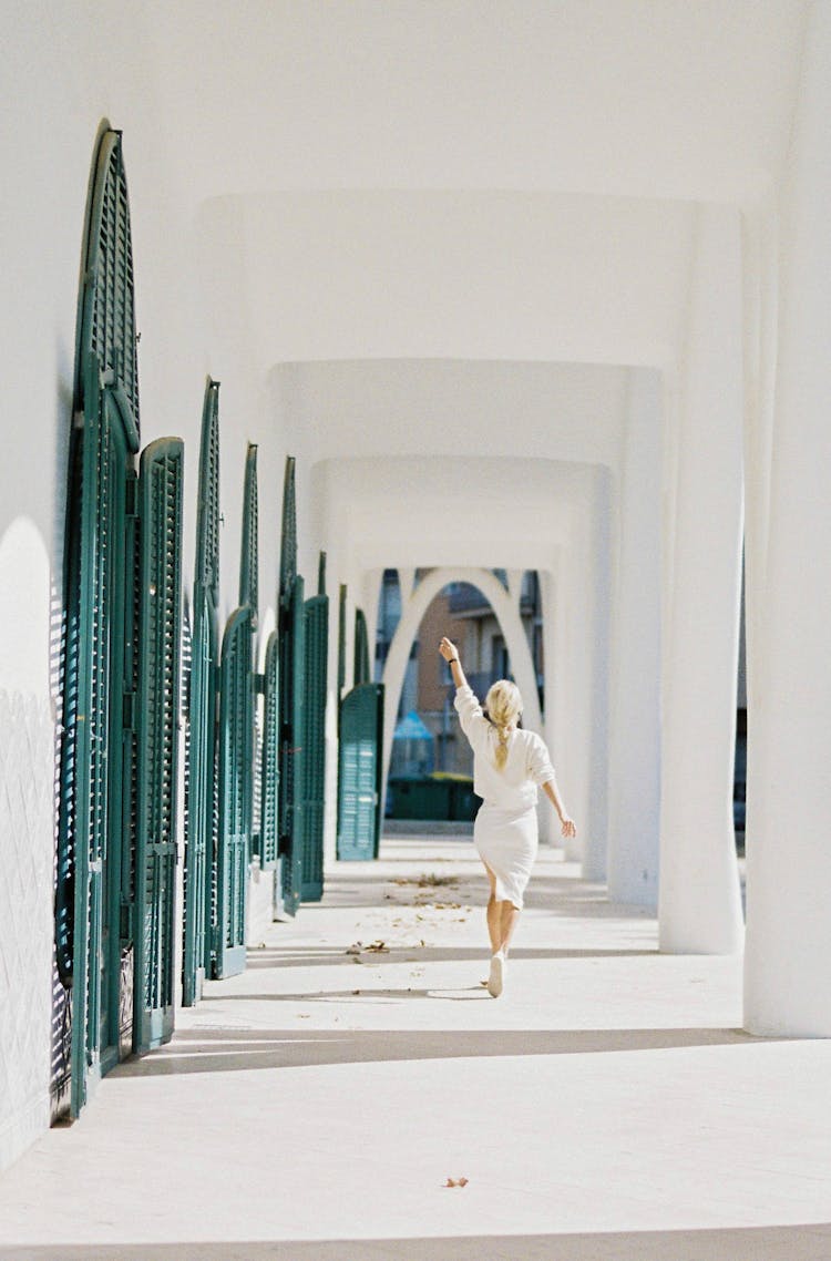 Woman In White Clothes Having Fun Walking And Throwing Leaves On Outside Hallway Of A House