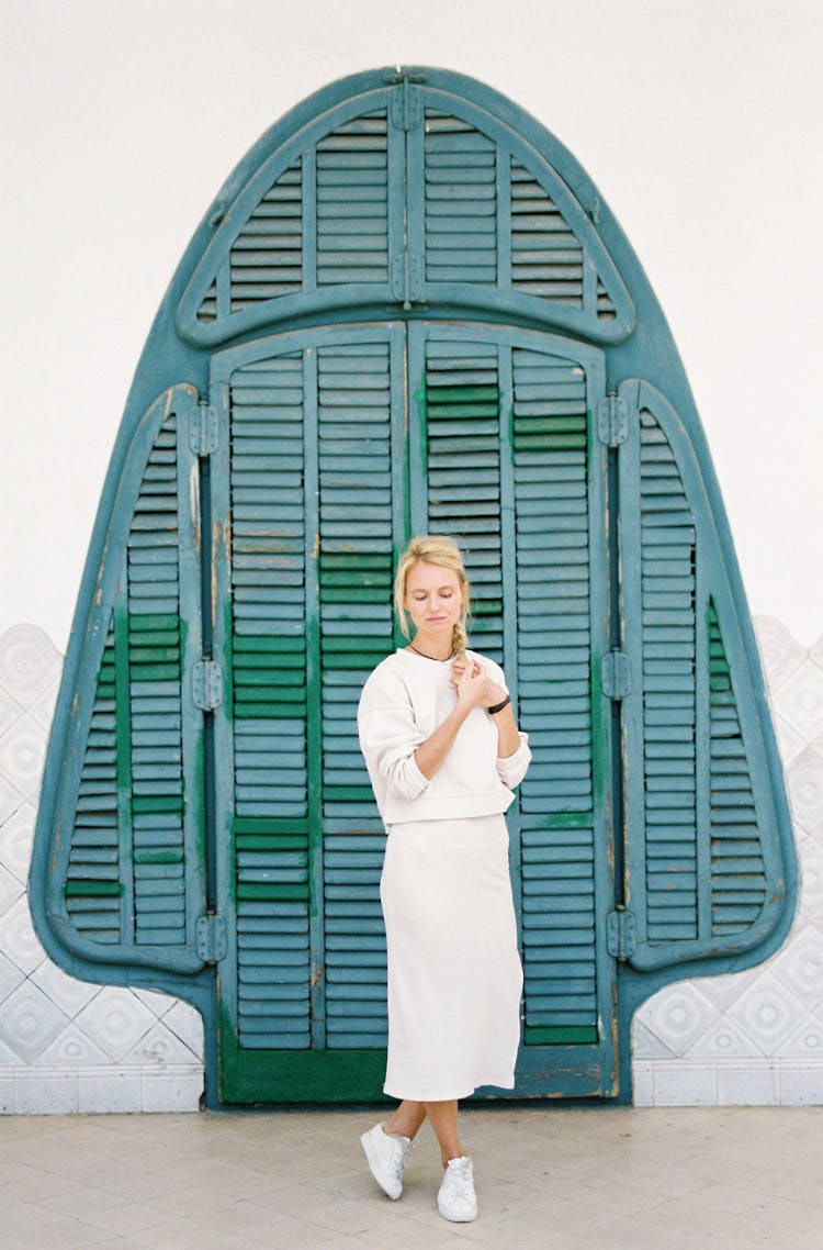 Woman In White Skirt Standing By Wooden Door