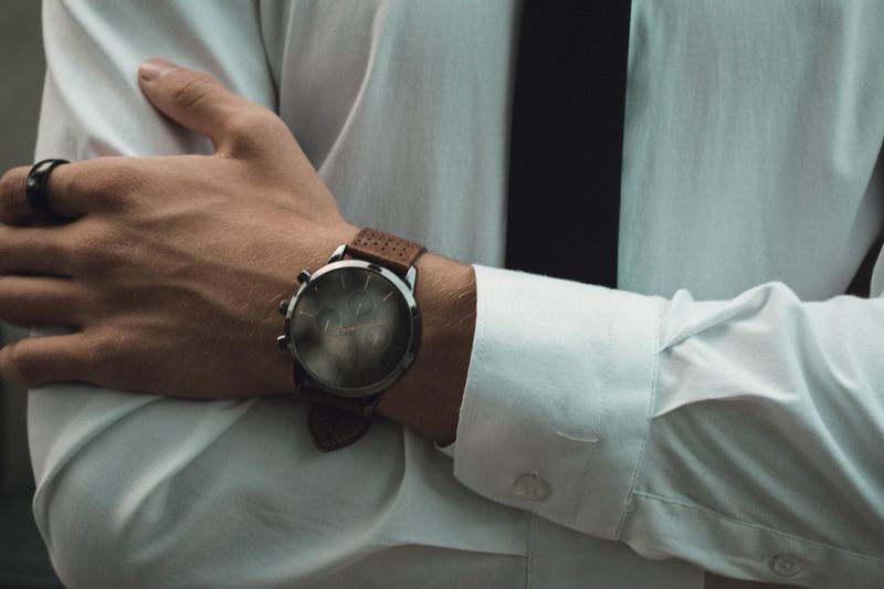 A watch worn at the cuff of a white shirt — photo by Iulian Patrascu on Pexels