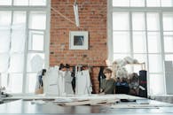 一位设计师在时尚工作室工作，那里通风良好，有砖墙和大窗户