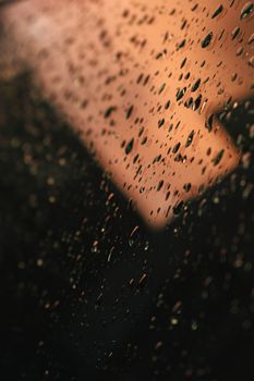 玻璃上的水滴特写，以温暖的背景创造出抽象图案