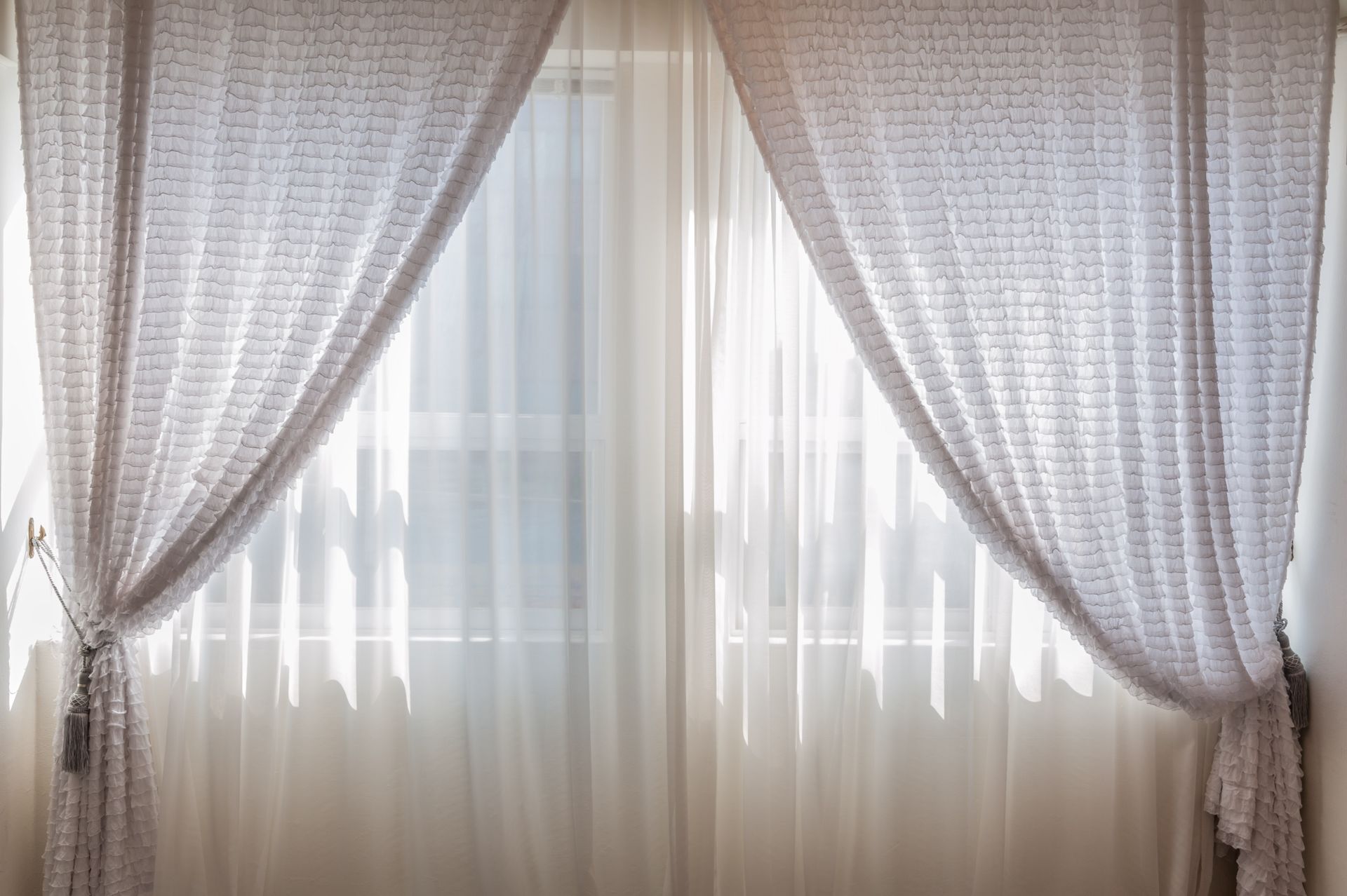 Sun shining through elegant white curtains in a cozy, modern interior setting.