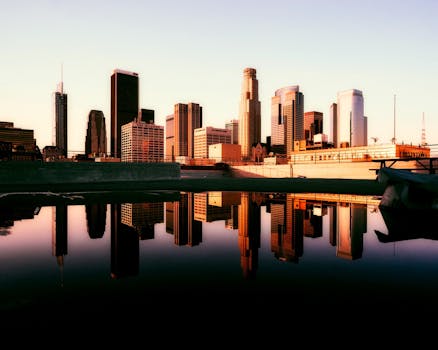 Stunning reflection of Los Angeles skyline during sunset, showcasing modern skyscrapers and urban beauty.