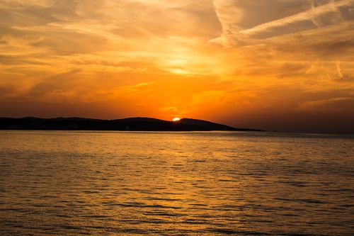 Free Stunning orange sunset over the ocean with a peaceful horizon. Perfect for seascape lovers. Stock Photo