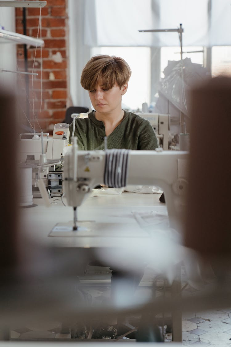 Woman In Green And White Stripe Polo Shirt Standing In Front Of Sewing Machine