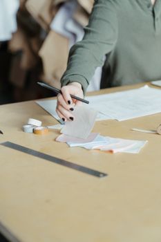 在缝纫车间环境中，设计师正在手工检查面料样本的特写