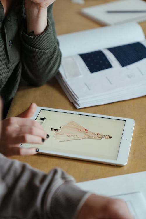 Person in Gray Sweater Holding White Tablet Computer