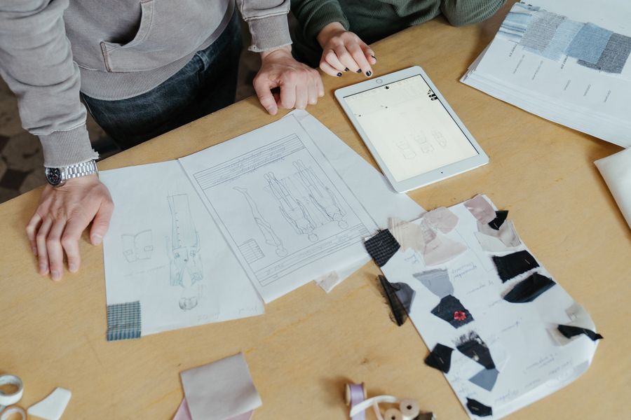 Two designers examining clothing sketches and fabric swatches