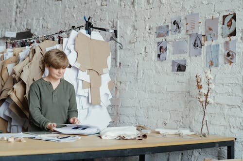 Woman in Green Long Sleeve Shirt Writing on White Paper