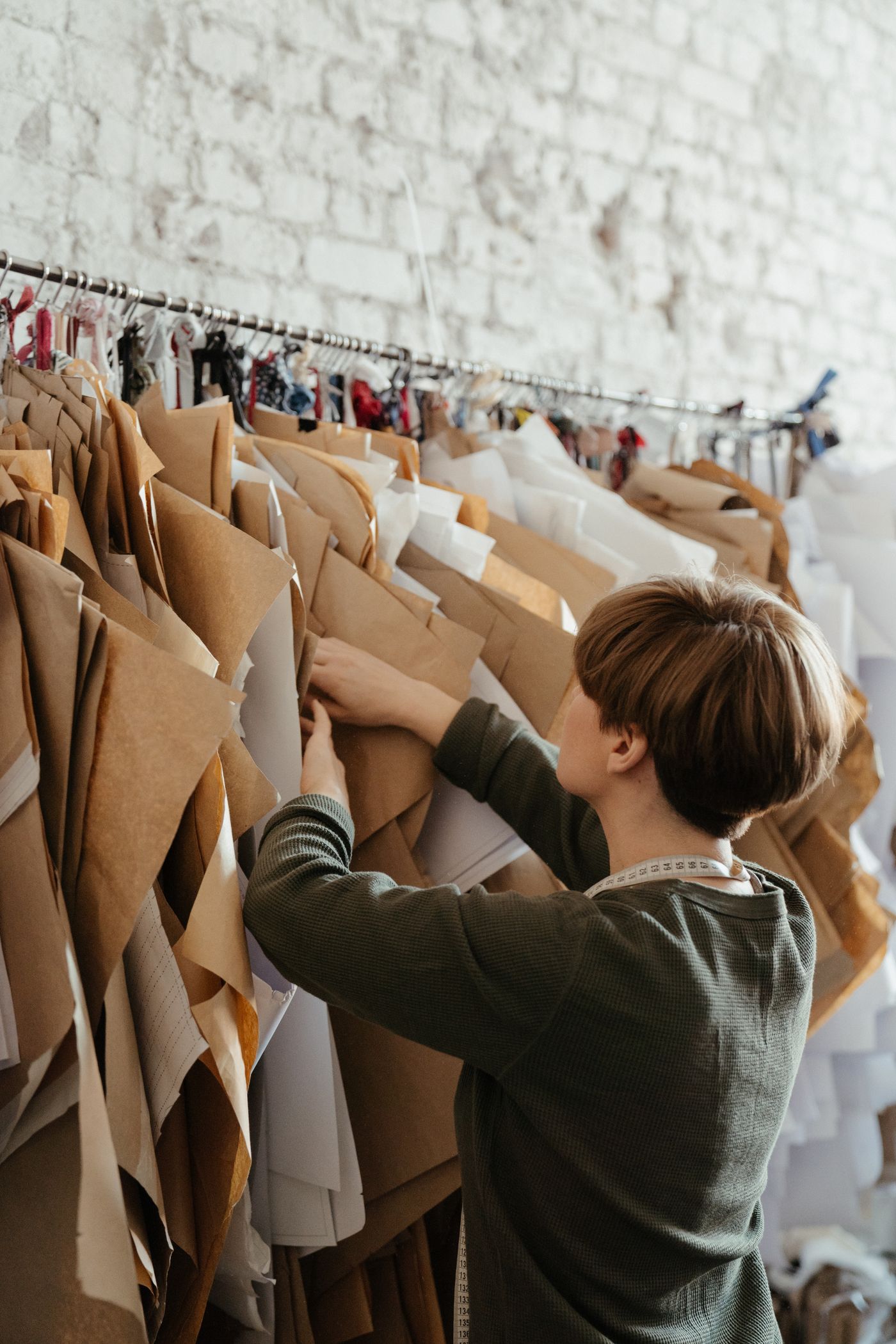Paper patterns hanging in an atelier — the working library behind every piece.