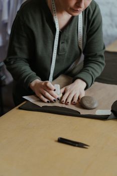 时装设计师在工作室里，正往布料上标记图案，展示定制剪裁