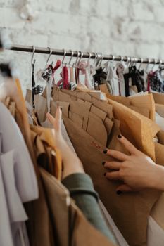 Close-up of hands sorting assorted sewing patterns on a rack in a fashion design studio.