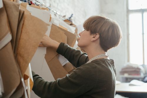 Free A designer arranges paper patterns in a sewing studio, highlighting creativity and organization. Stock Photo