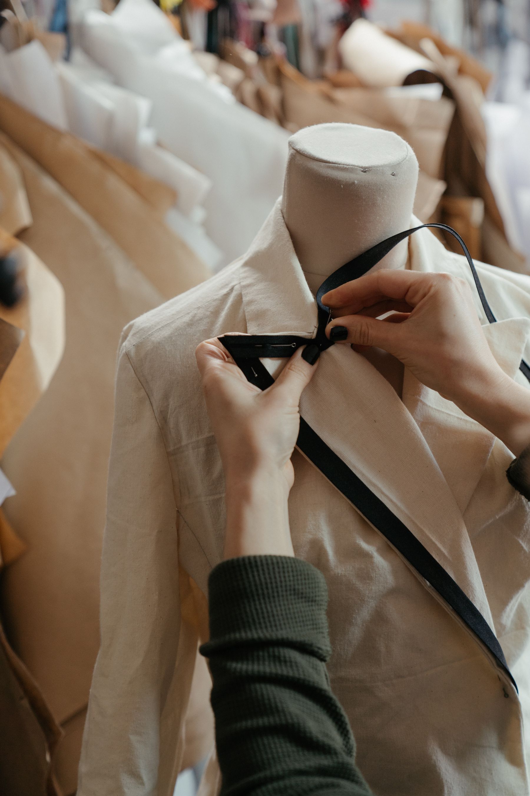 A jacket being adjusted on a dress stand in a working atelier